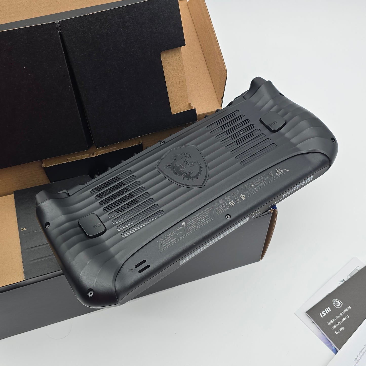 Black electronic device on a white surface with packaging materials underneath
