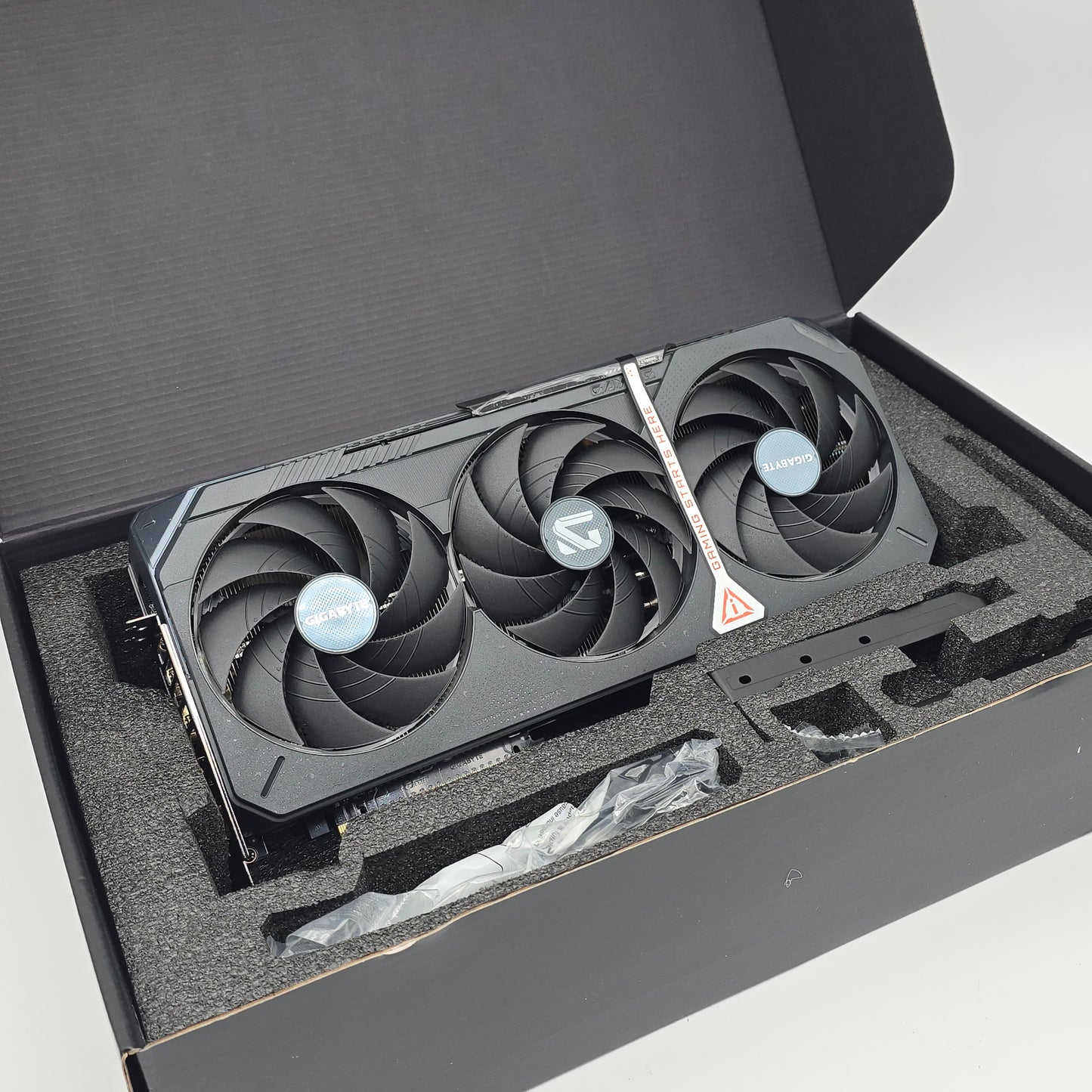 Graphics card with three fans in a black box, appears to be rtx 5090 gigabyte gaming oc model graphics card for a high end gaming computer, open box but new