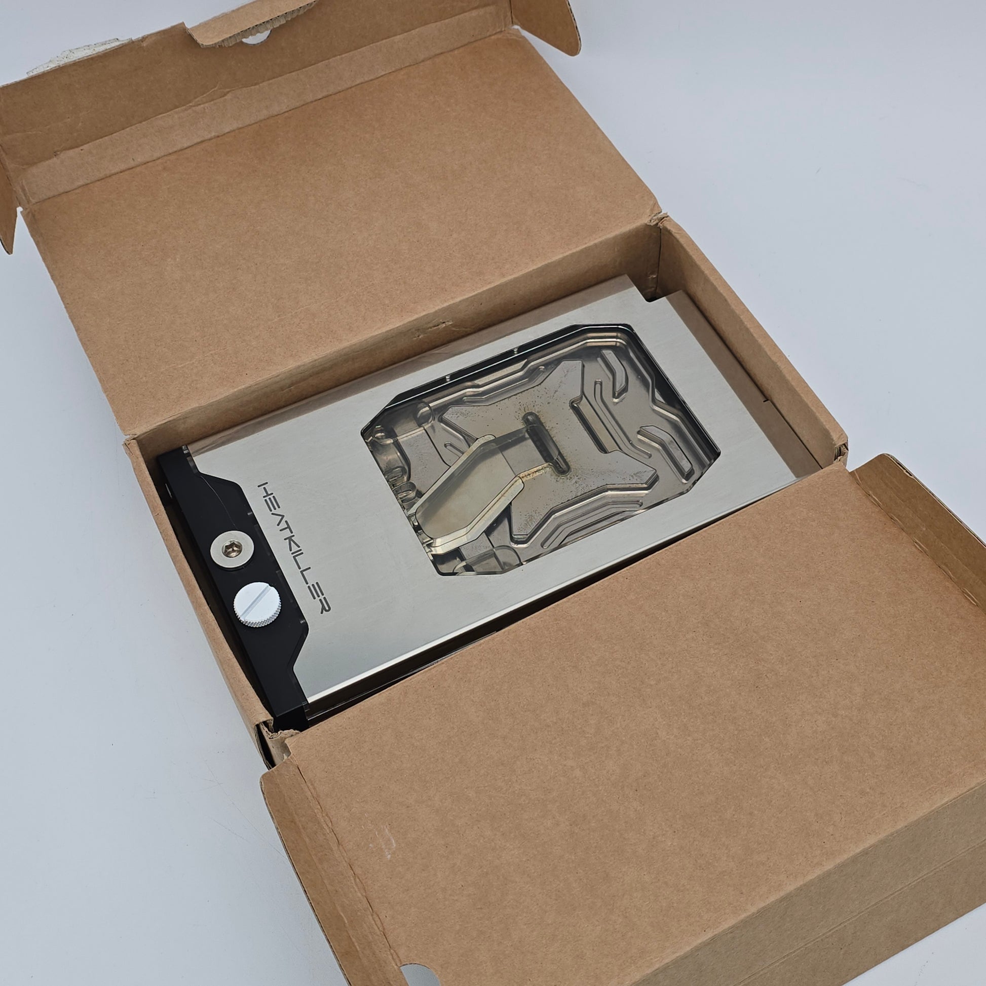 Metallic device with 'HEATKILLER' branding inside an open cardboard box.
