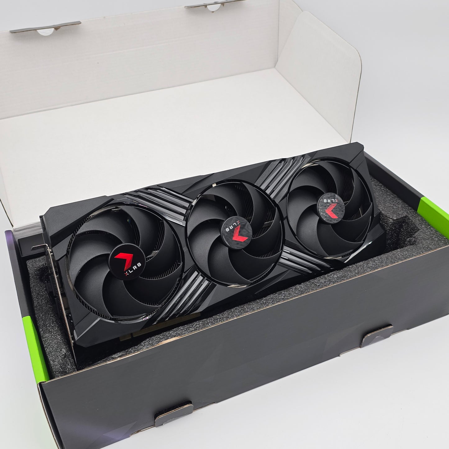 Gaming graphics card with three fans in an open box on a white background