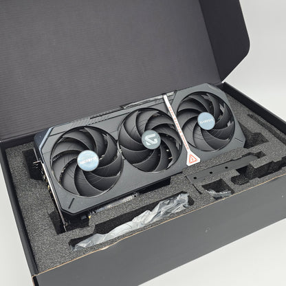 Graphics card with three fans in a black box, appears to be rtx 5090 gigabyte gaming oc model graphics card for a high end gaming computer, open box but new